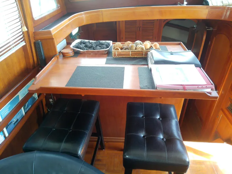 Slide: The Image of Interior of 1987 Albin 40 boat with wooden table and black cushioned stools. - 24
