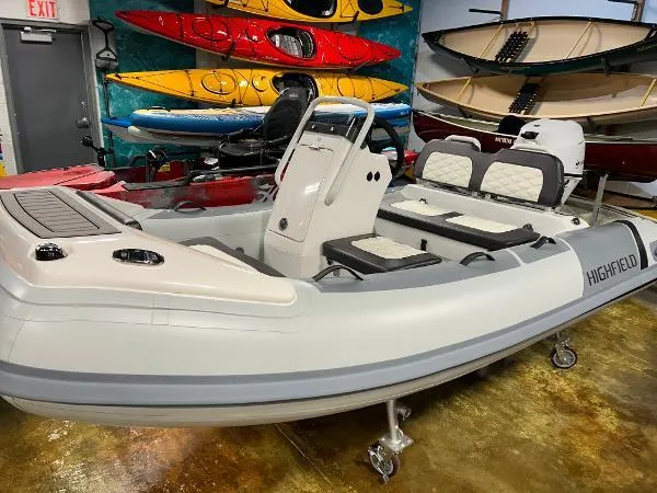 Slide: The Image of 2023 Highfield Sport 330 inflatable boat displayed indoors with colorful kayaks in the background. - 11