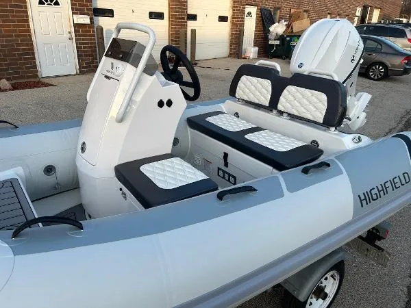 Slide: The Image of 2023 Highfield Sport 330 inflatable boat with white seating and steering console, parked on a trailer. - 13