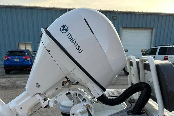 Slide: The Image of Tohatsu outboard motor on 2023 Highfield Sport 330 boat, parked near industrial building. - 15