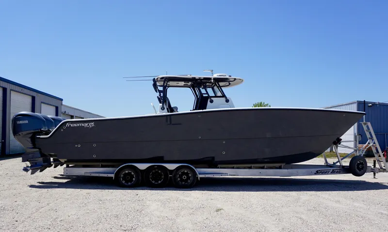 Slide: The Image of 2020 Freeman 37 VH boat on trailer, side view, parked outdoors under clear blue sky. - 16
