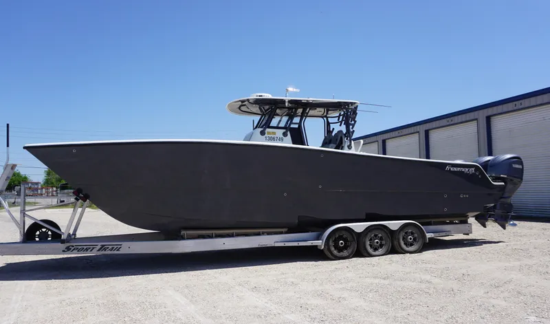 Slide: The Image of Freeman 37 VH 2020 boat on trailer, parked outdoors near storage units. - 2