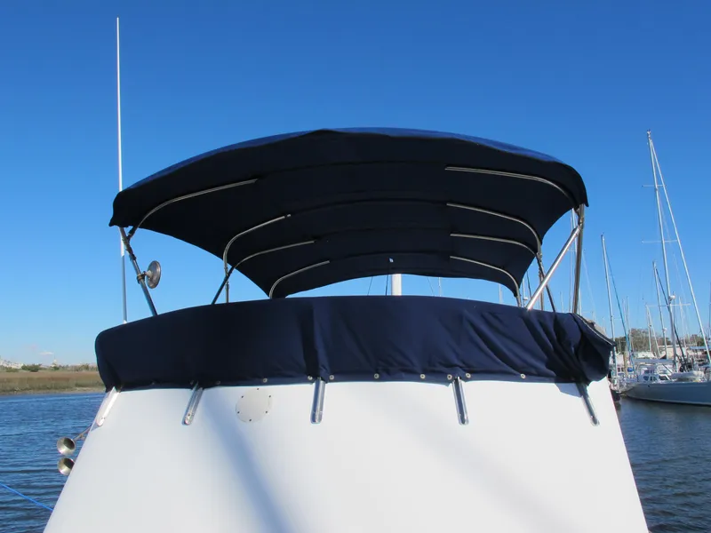 Slide: The Image of 1986 Monk 36 boat with blue canopy, docked under clear blue sky. - 10