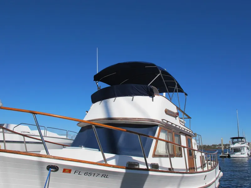 Slide: The Image of 1986 Monk 36 boat with blue canopy, docked under clear blue sky. - 2