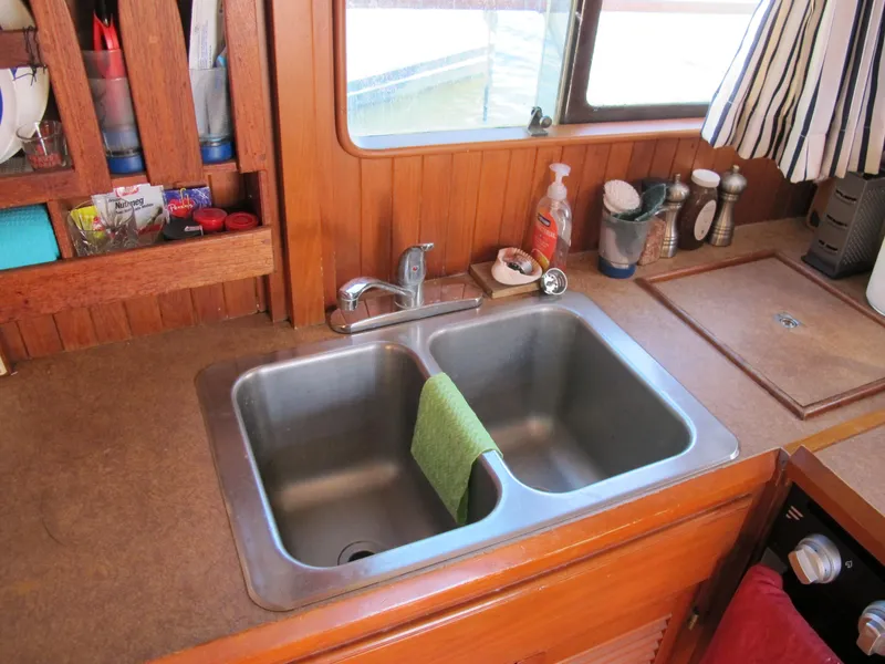 Slide: The Image of Kitchen sink area in a 1986 Monk 36 boat, featuring a double basin and wooden cabinetry. - 22