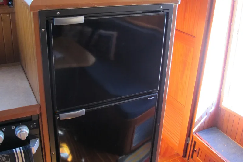 Slide: The Image of Black refrigerator in a 1986 Monk 36 boat interior kitchen area. - 27