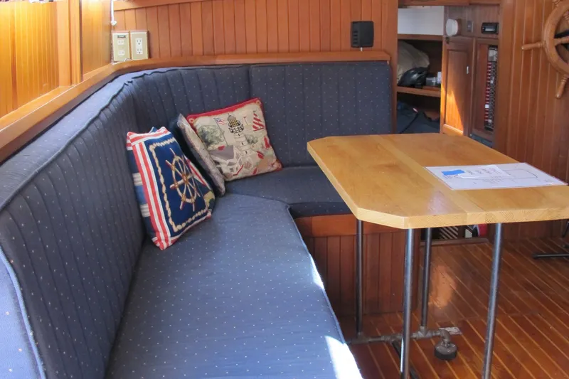 Slide: The Image of Cozy seating area in a 1986 Monk 36 boat with nautical-themed cushions and wooden table. - 29