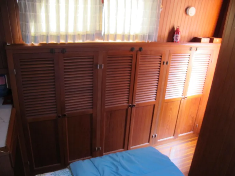 Slide: The Image of Wooden interior of 1986 Monk 36 boat with louvered cabinets and a bed. - 32