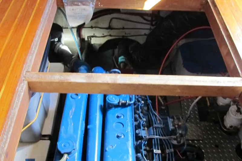 Slide: The Image of Engine compartment of a 1986 Monk 36 boat, featuring a blue engine and wooden flooring. - 47