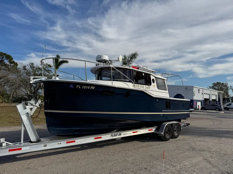 The Image of 2019 Ranger Tugs R-27 boat on trailer, parked outdoors under a cloudy sky. - 1