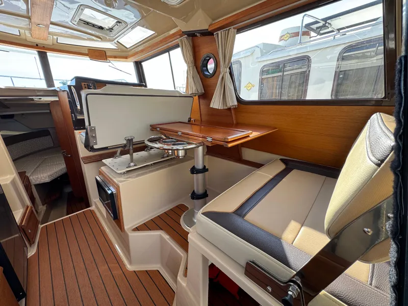 Slide: The Image of 2019 Ranger Tugs R-27 interior with wood accents, seating, and dining area. - 5