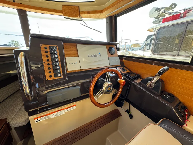 Slide: The Image of 2019 Ranger Tugs R-27 helm with Garmin navigation system and wooden steering wheel. - 7