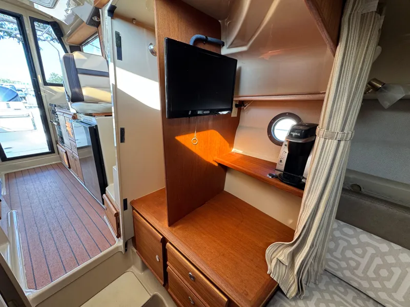 Slide: The Image of 2019 Ranger Tugs R-27 interior with TV, wooden cabinetry, and cozy seating area. - 9