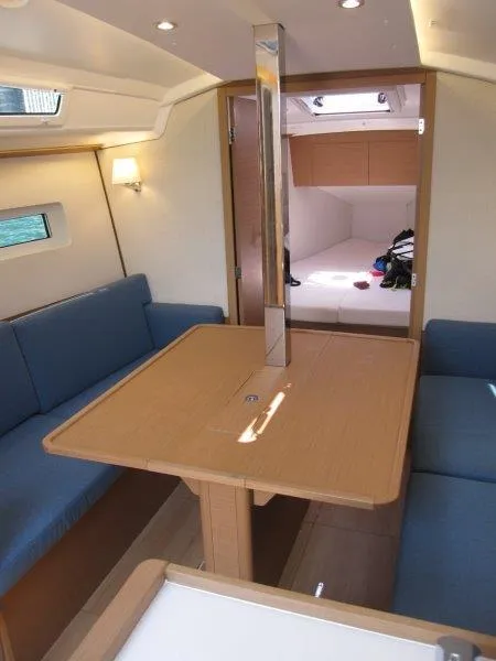 Slide: The Image of Interior of 2025 Jeanneau Sun Odyssey 350 sailboat with blue seating and wooden table. - 31