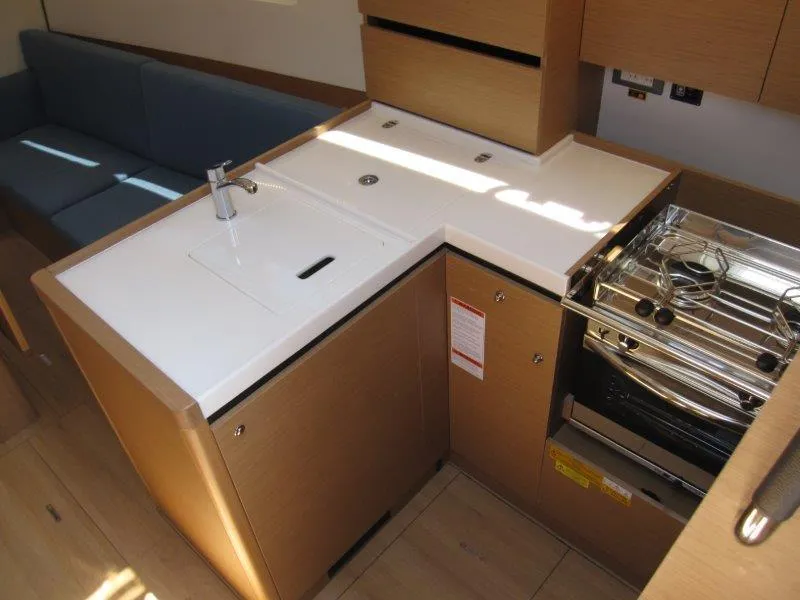 Slide: The Image of Modern kitchen in 2025 Jeanneau Sun Odyssey 350 yacht, featuring sleek countertops and compact stove. - 13