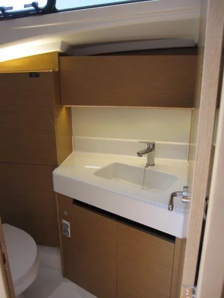 Slide: The Image of 2025 Jeanneau Sun Odyssey 350 bathroom interior with modern sink and wooden cabinetry. - 14