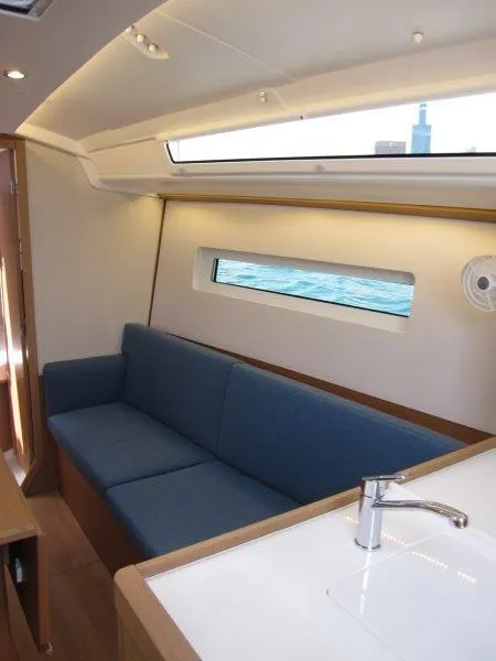 Slide: The Image of 2025 Jeanneau Sun Odyssey 350 interior with blue sofa and modern design. - 6