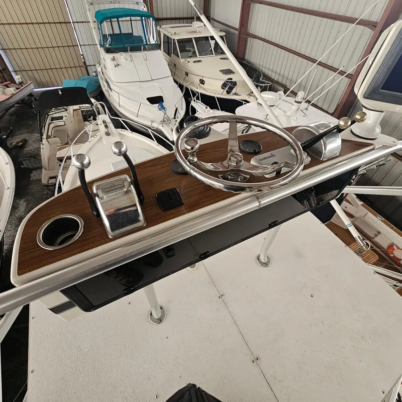 Slide: The Image of 1994 Blackfin 33 Combi helm with steering wheel and controls in a boat storage facility. - 22