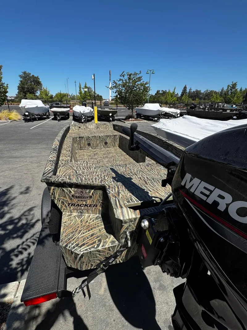 Slide: The Image of 2025 Tracker Grizzly 1650 T Prairie Wings Edition boat with camouflage design in parking lot. - 2