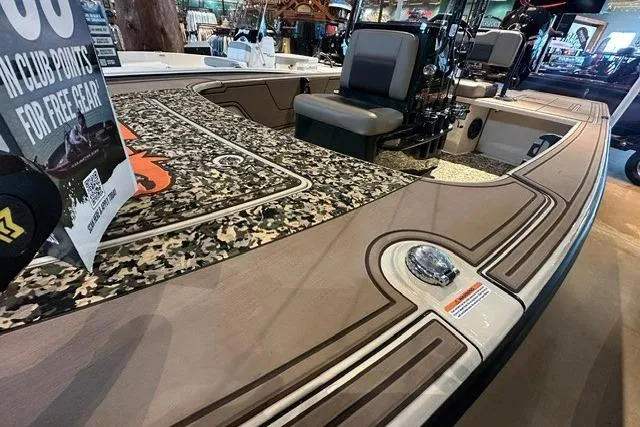 Slide: The Image of 2025 Mako 18 Pro Skiff Backwater Edition with camo deck and seating, showcased indoors. - 9