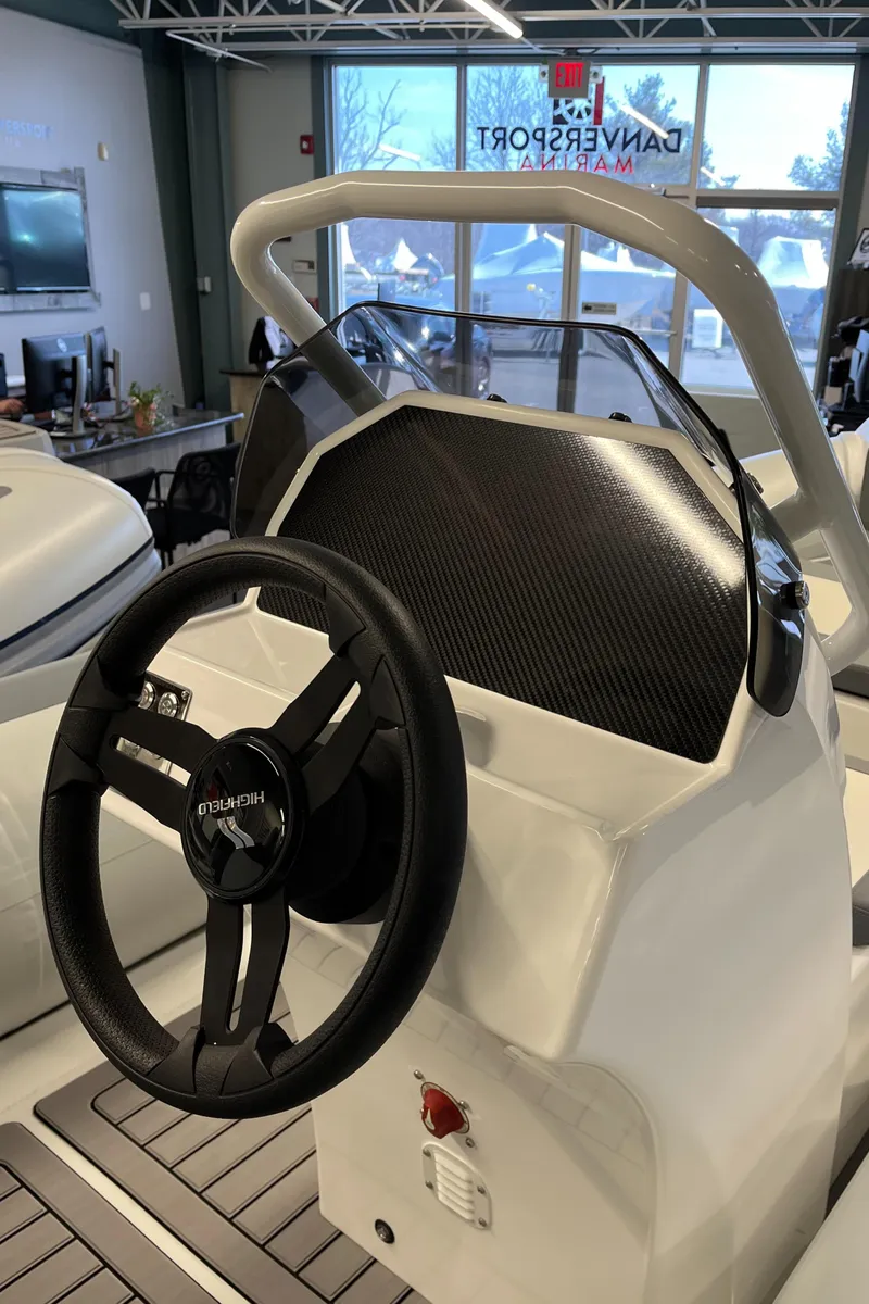 Slide: The Image of 2025 Highfield Classic 400 boat steering console with carbon fiber accents in showroom. - 3