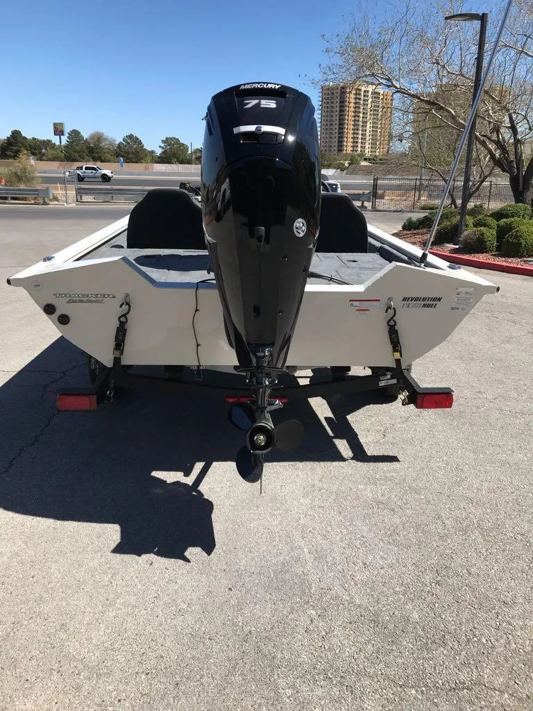 Slide: The Image of 2025 Tracker Pro Team 175 boat with outboard motor in a parking lot. - 2