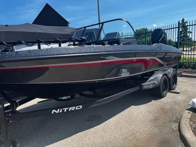 The Image of 2025 Nitro ZV21 Pro boat on trailer, sleek design, black with red accents, parked outdoors. - 0