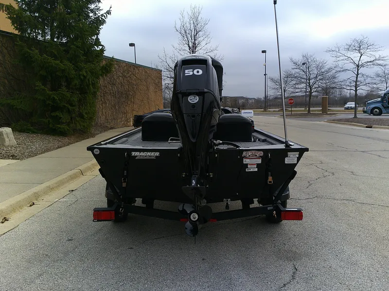 Slide: The Image of 2025 Tracker Pro 170 boat with 50 HP motor parked on a street. - 2