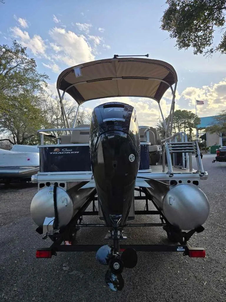 Slide: The Image of 2025 Sun Tracker Bass Buggy 18 DLX pontoon boat with canopy, parked outdoors. - 3