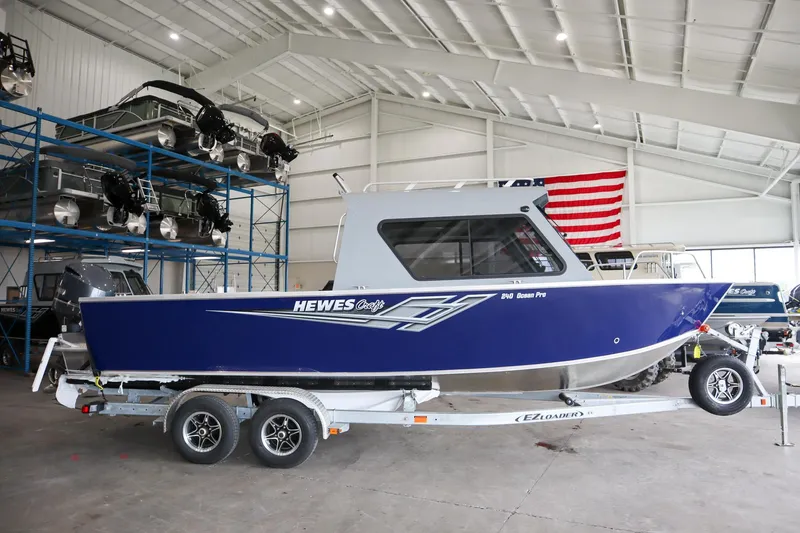 Slide: The Image of 2025 Hewescraft 240 Ocean Pro ET HT boat in showroom, blue exterior, on trailer. - 1