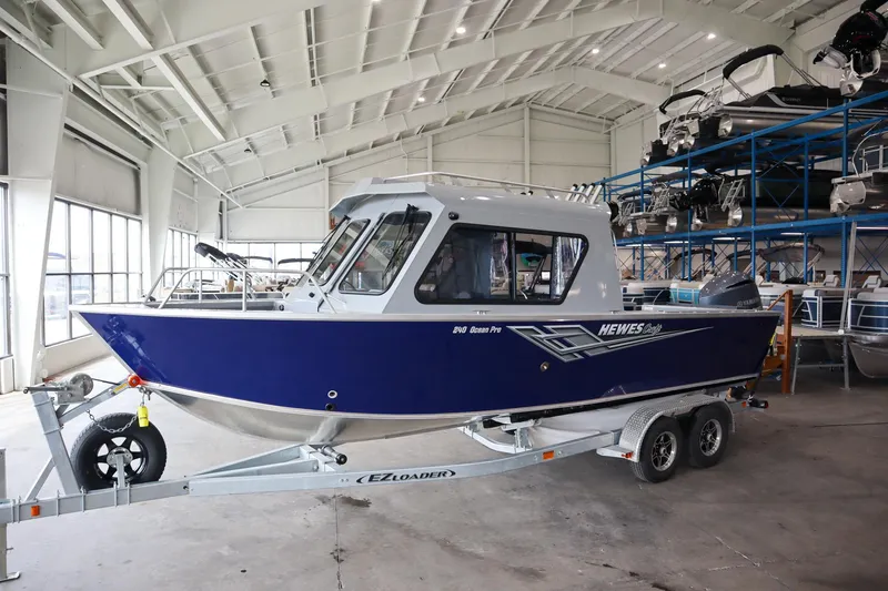 Slide: The Image of 2025 Hewescraft 240 Ocean Pro ET HT boat in a showroom on a trailer. - 2