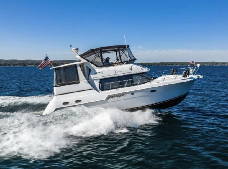 Slide: The Image of 2000 Carver 406 Aft Cabin Motor Yacht cruising on open water under clear blue skies. - 0