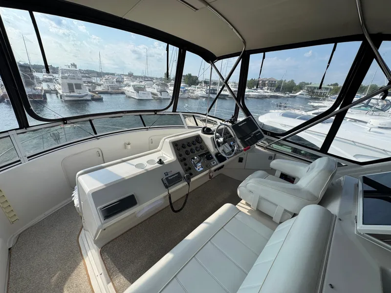 Slide: The Image of 2000 Carver 406 Aft Cabin Motor Yacht helm with marina view, featuring modern controls and seating. - 22