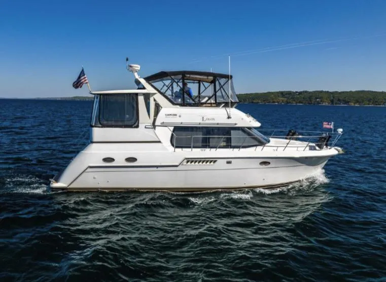 Slide: The Image of 2000 Carver 406 Aft Cabin Motor Yacht cruising on open water under clear skies. - 5