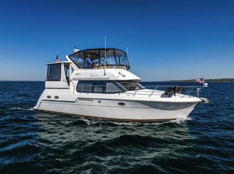 Slide: The Image of 2000 Carver 406 Aft Cabin Motor Yacht cruising on open water under clear blue sky. - 6