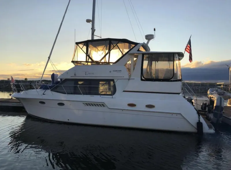 Slide: The Image of 2000 Carver 406 Aft Cabin Motor Yacht docked at sunset with American flag. - 8