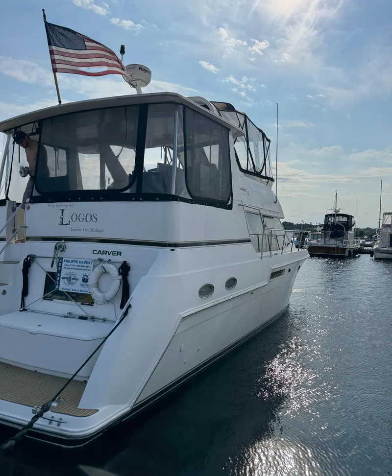 Slide: The Image of 2000 Carver 406 Aft Cabin Motor Yacht docked, American flag waving, sunny day. - 9
