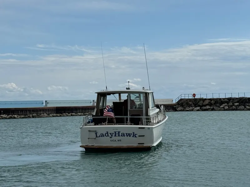 Slide: The Image of 1969 Chris-Craft Commander boat "LadyHawk" cruising on a calm lake near a rocky pier. - 20