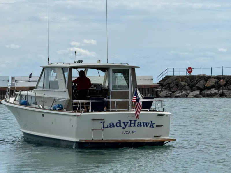 Slide: The Image of 1969 Chris-Craft Commander boat "LadyHawk" on water near rocky shore. - 22