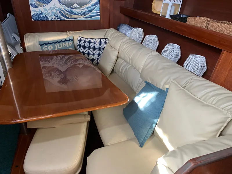 Slide: The Image of Cozy interior of 2001 Hunter Passage 450 yacht with cushioned seating and wooden table. - 12