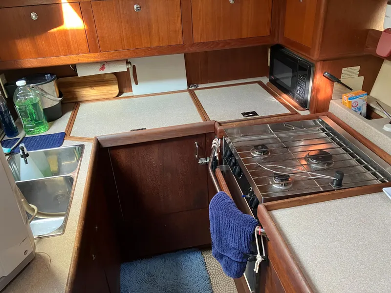 Slide: The Image of Compact kitchen in a 2001 Hunter Passage 450 yacht with stove, sink, and wooden cabinetry. - 30