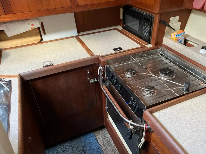 Slide: The Image of 2001 Hunter Passage 450 yacht kitchen with stove, microwave, and wooden cabinetry. - 6