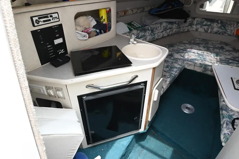 Slide: The Image of 1998 Sea Ray 240 Sundancer cabin interior with kitchenette, sink, and seating area. - 17