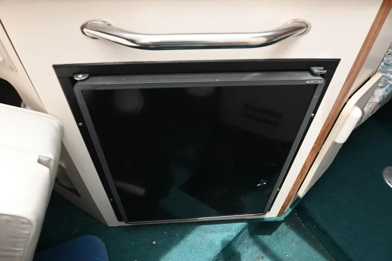 Slide: The Image of 1998 Sea Ray 240 Sundancer interior with built-in refrigerator and teal carpet. - 18