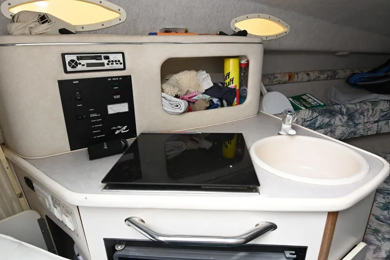 Slide: The Image of 1998 Sea Ray 240 Sundancer cabin with kitchenette, sink, and storage area. - 19