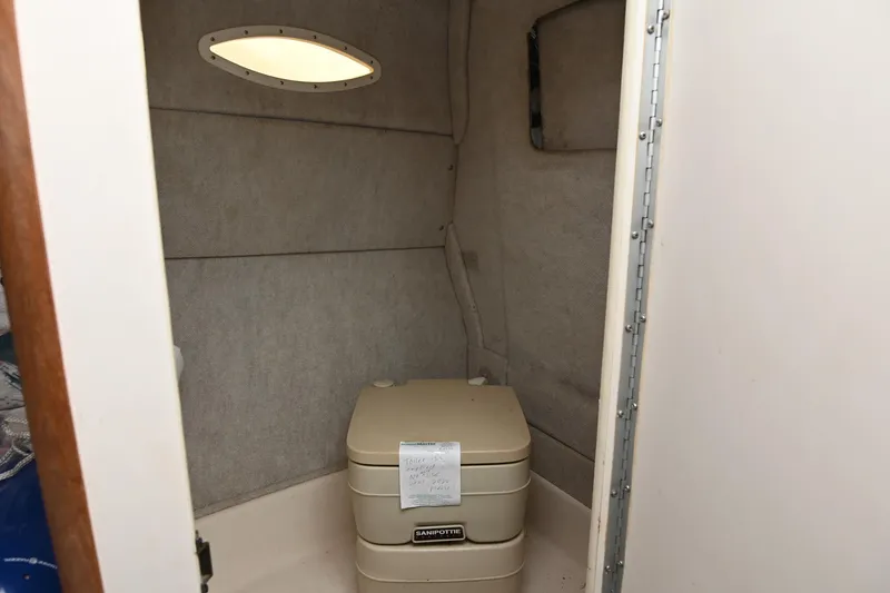 Slide: The Image of 1998 Sea Ray 240 Sundancer cabin with portable toilet and small window. - 25