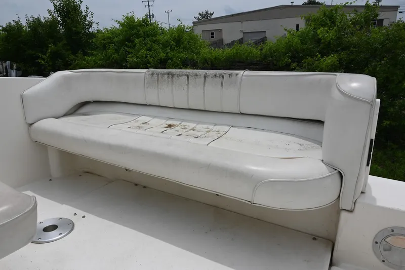 Slide: The Image of Worn white seating on 1998 Sea Ray 240 Sundancer boat, surrounded by greenery. - 7