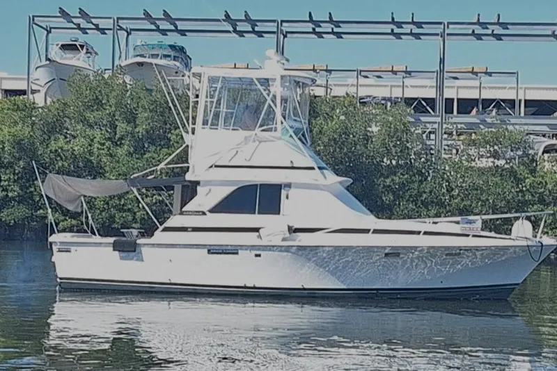 Slide: The Image of 1979 Bertram 35 Sport Fisherman boat docked near lush greenery. - 0