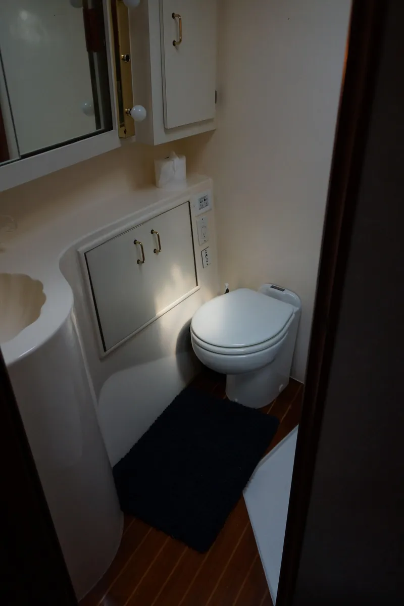 Slide: The Image of 1988 Ocean Yachts Super Sport bathroom with toilet, cabinets, and wooden flooring. - 14