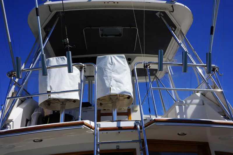 Slide: The Image of 1988 Ocean Yachts Super Sport boat deck with covered seats and metal railings under clear blue sky. - 22